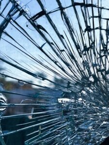 Home Detailed image of fractured glass with intricate patterns and blue sky in the background.