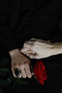 Home Dramatic capture of intertwined hands with a vibrant red rose symbolizing love and connection.